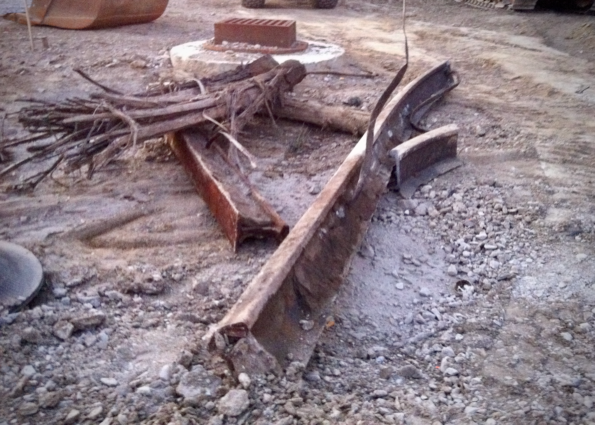 Broken, rusted steel rails and splintered wood remnants lie on loose gravel at a road construction site where a streetcar line has been removed.